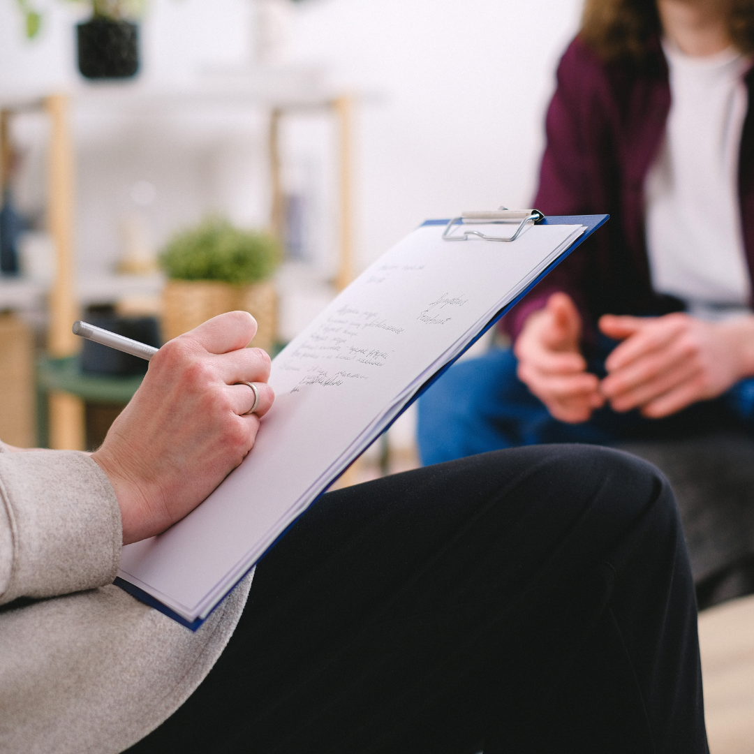 Therapist writing on clipboard